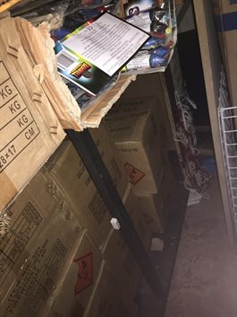 Firework boxes open and stored loosely on shelving with flammable material