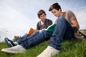 Two teenage friends reading on grass
