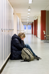 Upset girl leaning against shcool lockers